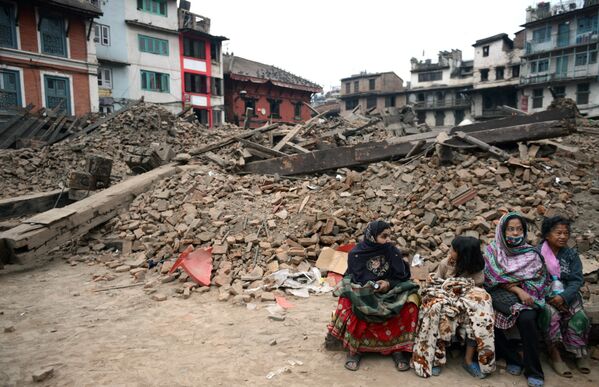 Жители сидят возле разрушенного здания в Катманду, Непал