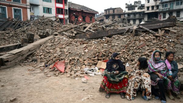 Жители сидят возле разрушенного здания в Катманду, Непал. Архивное фото