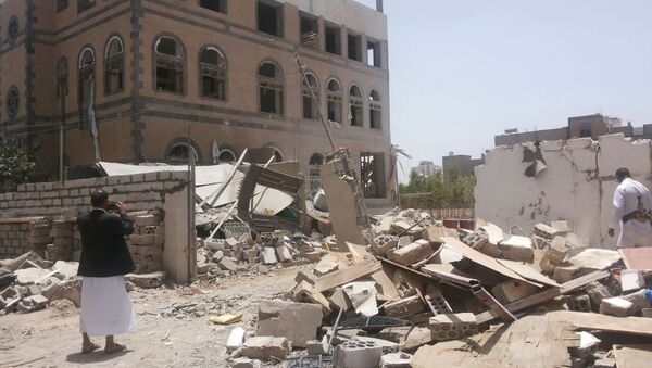 Мужчина фотографирует разрушеное здание в Сане, Йемен