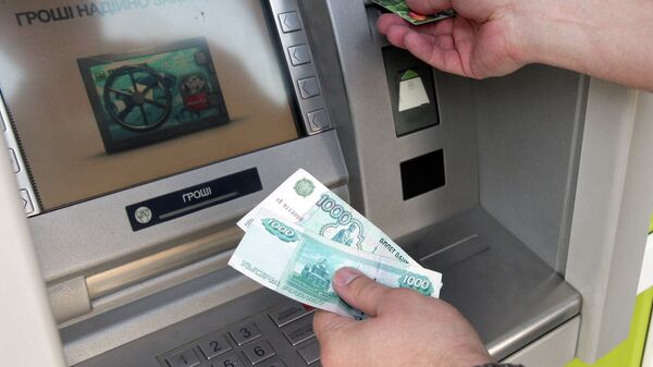 Житель снимает наличные денеги через банкомат. Архивное фото
