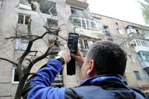 Сотрудник миссии ОБСЕ осматривает дом, поврежденный в результате обстрела Донецка