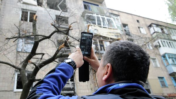 Сотрудник миссии ОБСЕ осматривает дом, поврежденный в результате обстрела Донецка. Архивное фото