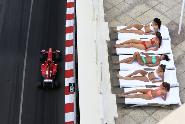 Болид бразильского автогонщика Фелипе Масса проезжает мимо загорающих девушек в Монако в преддверии Гран-при Формулы-1. 2013 год