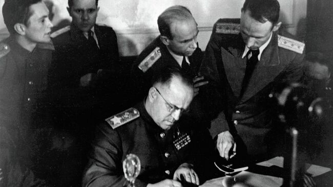 Маршал Советского Союза Георгий Константинович Жуков (в центре) подписывает Акт о безоговорочной капитуляции фашистской Германии в Карлсхорсте в Берлине. Архив
