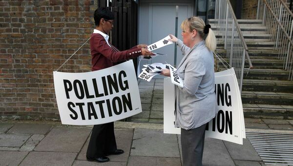 Сотрудницы избирательного участка в Ислингтоне размещают указатели. Архивное фото