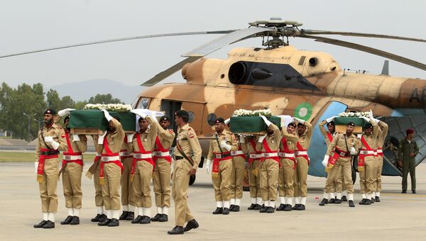 Пакистанские солдаты переносят погибших при крушении вертолета