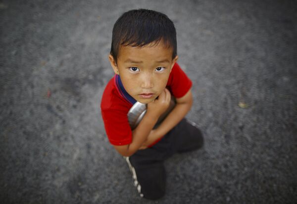 Мальчик стоит возле очереди за едой в Катманду