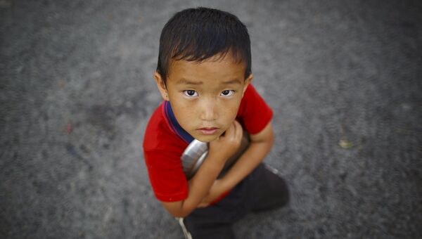 Мальчик стоит возле очереди за едой в Катманду