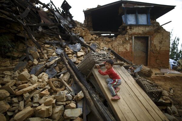 Мальчик играет на обломках разрушенного дома на окраине Катманду