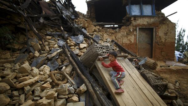 Мальчик играет на обломках разрушенного дома на окраине Катманду