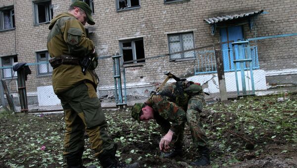 Ополченцы Донецкой народной республики (ДНР) измеряют воронку от снаряда у здания, пострадавшего в результате обстрелов украинскими силовиками города Горловки Донецкой области