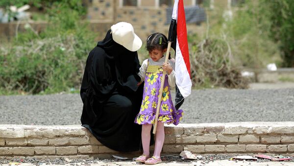 Женщина и ребенок с флагом Йемена во время митинга в Сане. Архивное фото