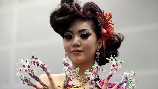 Модель представляет творение дизайнера во время конкурса парикмахерского искусства и искусства макияжа в Куала-Лумпуре