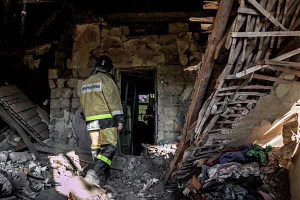 Сотрудник пожарной охраны в доме, разрушенном в результате обстрела украинскими силовиками в Донецке