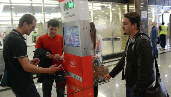 Пассажиры Московского метрополитена заряжают мобильные гаджеты у специального стенда на станции Выставочная. Архивное фото
