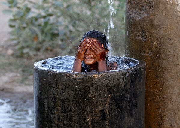 Девочка купается во время сильной жары на окраине Ахмедабада, Индия