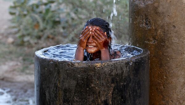 Девочка купается во время сильной жары на окраине Ахмедабада, Индия