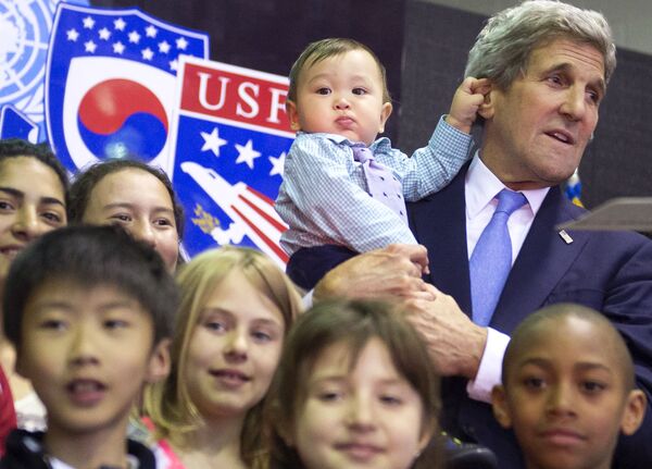 Госсекретарь США Джон Керри держит 8-ми месячного Эндрю Белза во время группового фотографирования с детьми американских военнослужащих