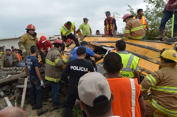 Полиция и пожарные осматривают обломки школьного автобуса после торнадо в Мексике
