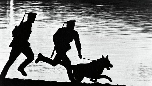 Пограничники с собакой бегут по берегу реки. Архивное фото