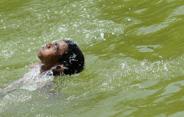 Мальчик прячется от жары в пруду Нью-Дели. Индия, май 2015