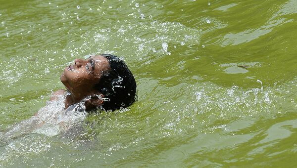 Мальчик прячется от жары в пруду Нью-Дели. Индия, май 2015