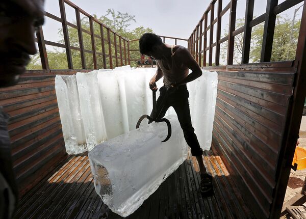 Рабочий ледяного производства грузит лед. Ахмедабад, Индия. Май 2015
