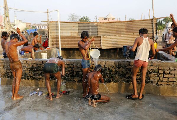 Рабочие на стройке принимают душ перед началом работы. Ахмедабад, Индия, май 2015