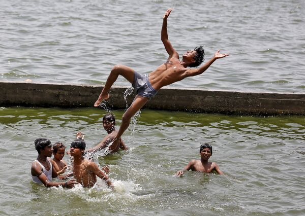 Мальчики спасаются от жары в реке Сабармати. Ахмедабаде, Индия, май 2015