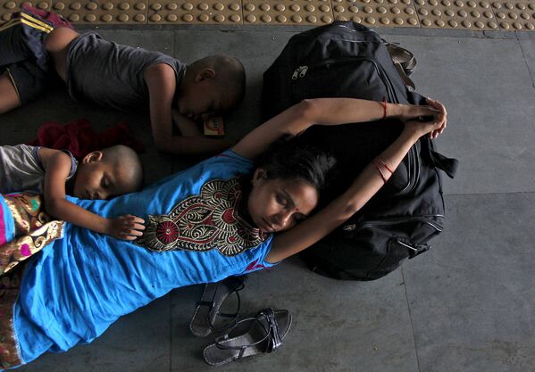 Женщина с детьми спиь на вокзале города Аллахабад. Индия, май 2015