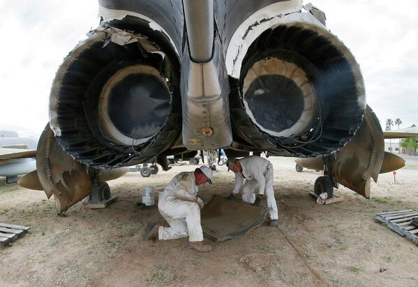 Военнослужащие 309-й группы по обслуживанию и ремонту авиакосмической техники снимают оборудование для крепления ракет с бомбардировщика F-4 Фантом на авиабазе ВВС США Девис-Монтен в Тусоне, Аризона
