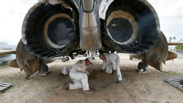 Военнослужащие 309-й группы по обслуживанию и ремонту авиакосмической техники снимают оборудование для крепления ракет с бомбардировщика F-4 Фантом на авиабазе ВВС США Девис-Монтен в Тусоне, Аризона