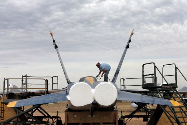 Военнослужащий покрывает водонепроницаемой краской американский истребитель-бомбардировщик F-18 на авиабазе ВВС США Девис-Монтен в Тусоне, Аризона