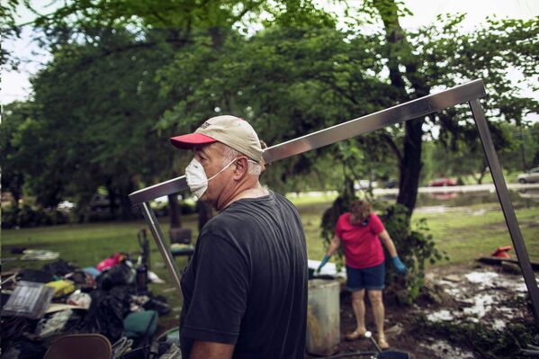 Человек убирает мусор из своего дома, разрушенного в результате наводнения в Техасе, США