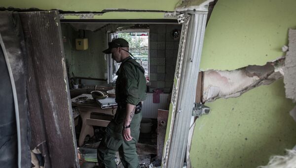 Ополченец Донецкой народной республики осматривает дом, разрушенный в результате обстрела украинскими силовиками в Горловке