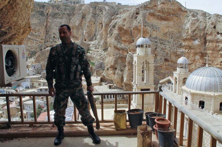 Военнослужащий сирийской армии на фоне церкви в городе Маалюля Военнослужащий сирийской армии на фоне церкви в городе Маалюля