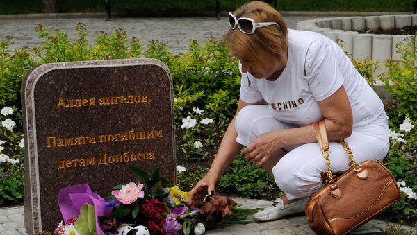 Жительница Донецка возлагает цветы к памятному камню Погибшим детям Донбасса. Архивное фото