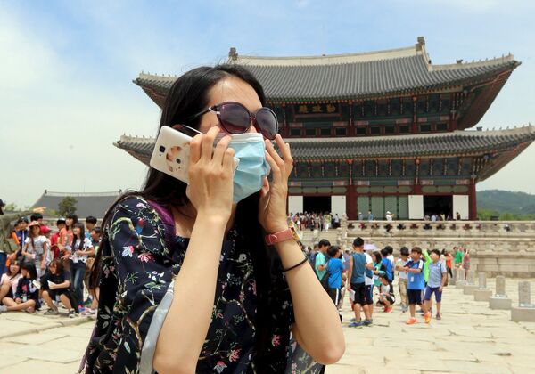 Женщина в защитной маске возле дворца Кёнбоккун в Сеуле во время вспышки вируса MERS в Южной Корее