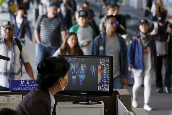 Пассажиры проходят мимо тепловизионной камеры в международном аэропорту Инчхон во время вспышки вируса MERS в Южной Корее