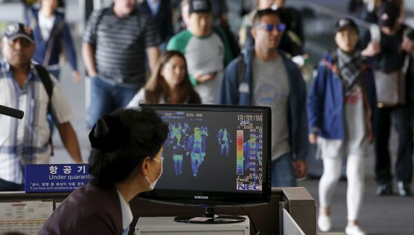 Пассажиры проходят мимо тепловизионной камеры в международном аэропорту Инчхон во время вспышки вируса MERS в Южной Корее