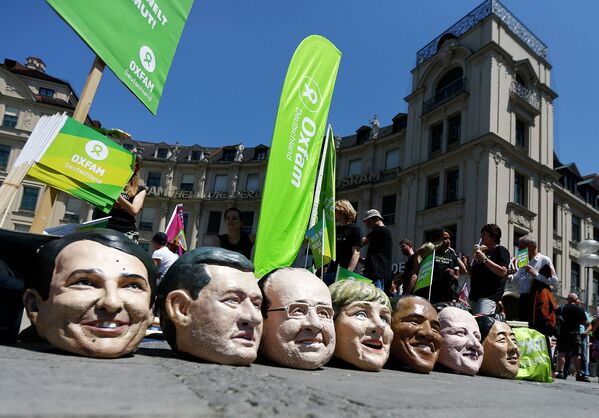 Участники акции протеста в Мюнхене приуроченной к саммиту G-7 с муляжами голов мировых лидеров