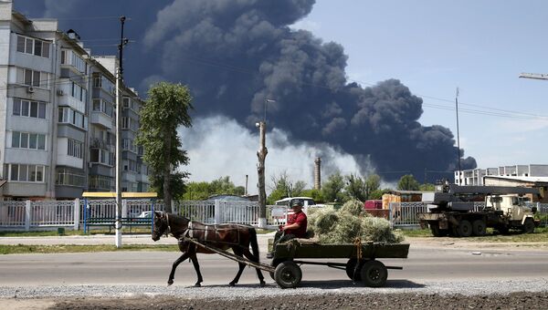 Житель проезжает мимо горящего нефтехранилищя в Киевской области, Украина. Июнь 2015