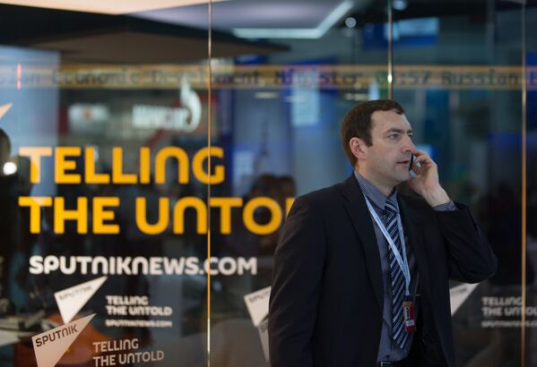 Участник форума разговаривает по телефону у павильона новостного агентства Sputnik на XIX Петербургском международном экономическом форуме