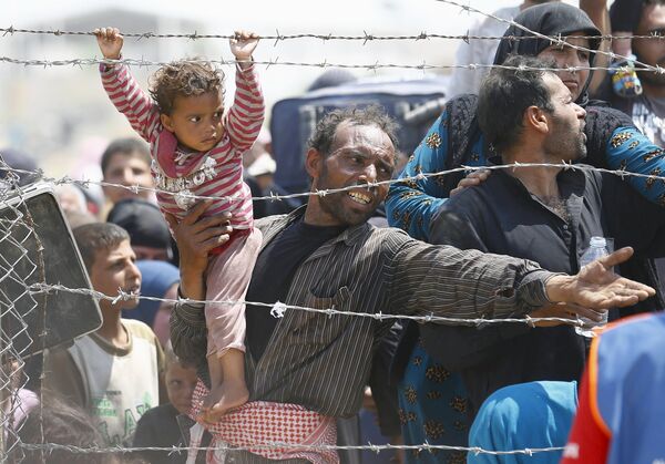 Сирийские беженцы у пограничного забора юго-востоке Турции