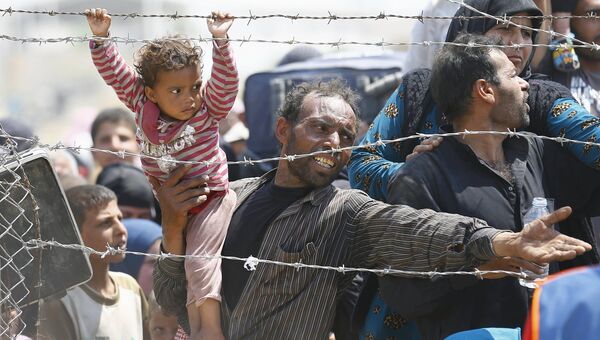 Сирийские беженцы у пограничного забора юго-востоке Турции