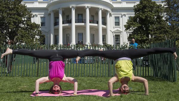 Две женщины занимаются йогой на лужайке перед Белым домом в Вашингтоне