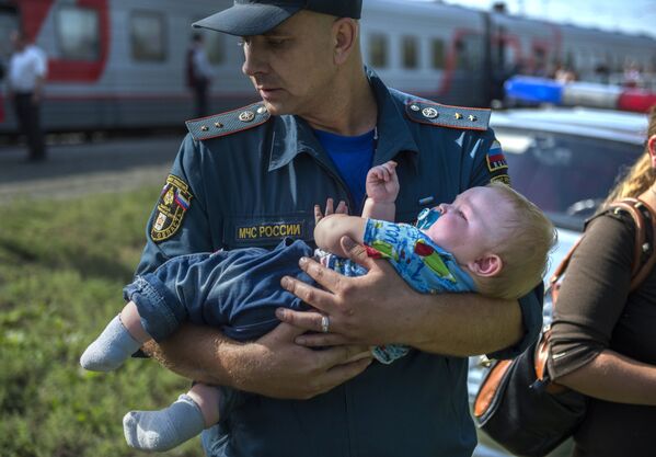 Сотрудник МЧС с ребенком во время встречи беженцев из Украины на железнодорожном вокзале в Омске