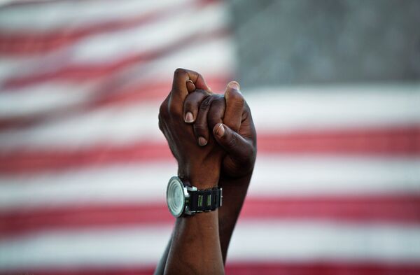Люди держатся за руки на фоне американского флага во время акции памяти погибшим в церкви 17 июня