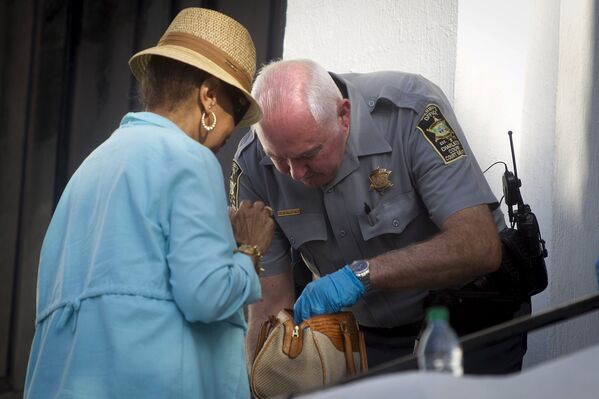 Полицейский проверяет сумки у прихожан пришедших на службу в вновь открытую церковь Эмануэль