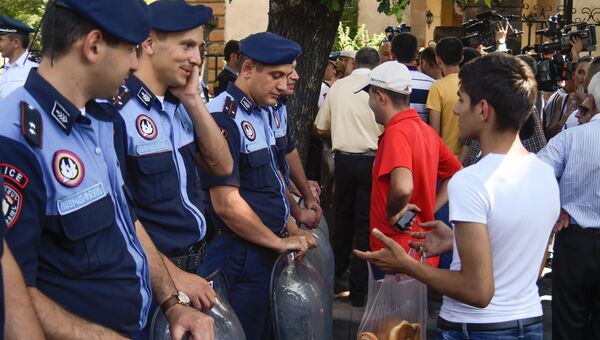 Горожанин предлагает выпечку сотрудникам правоохранительных органов во время масштабной акции протеста против повышения тарифов на электроэнергию